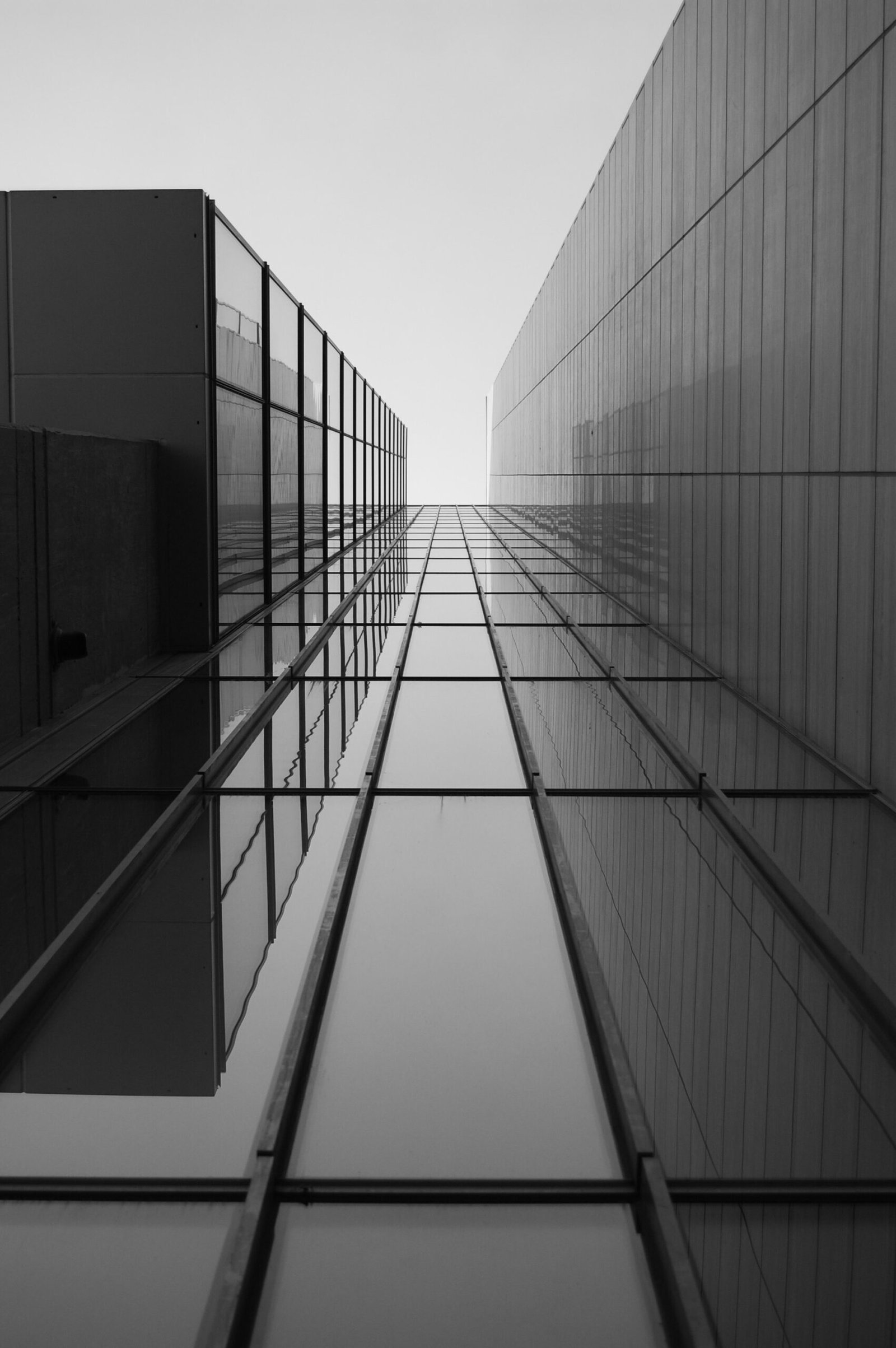 greyscale of a roof of a modern building with glass windows under sunlight